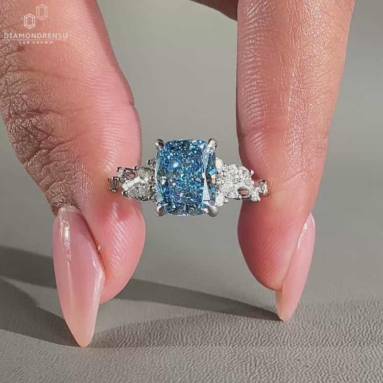 Elongated cushion ring with a sparkling blue diamond and a 4 prong claw setting.
