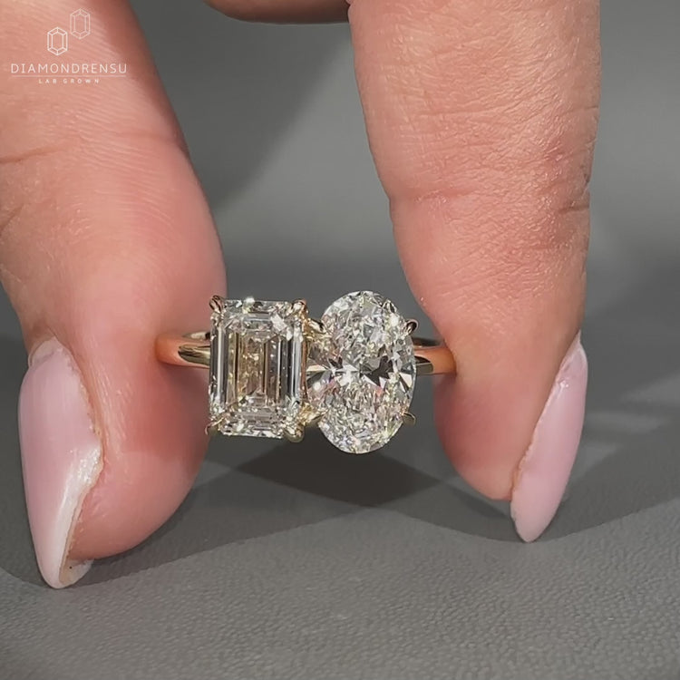 Oval and emerald diamond ring featuring two stone design and claw prong.
