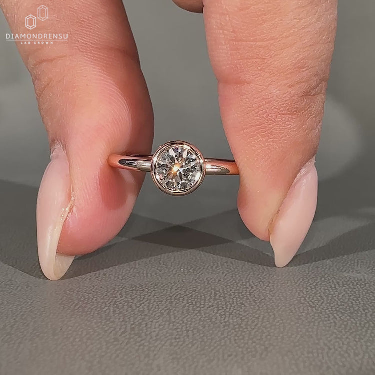 Round diamond ring with bezel set solitaire design.