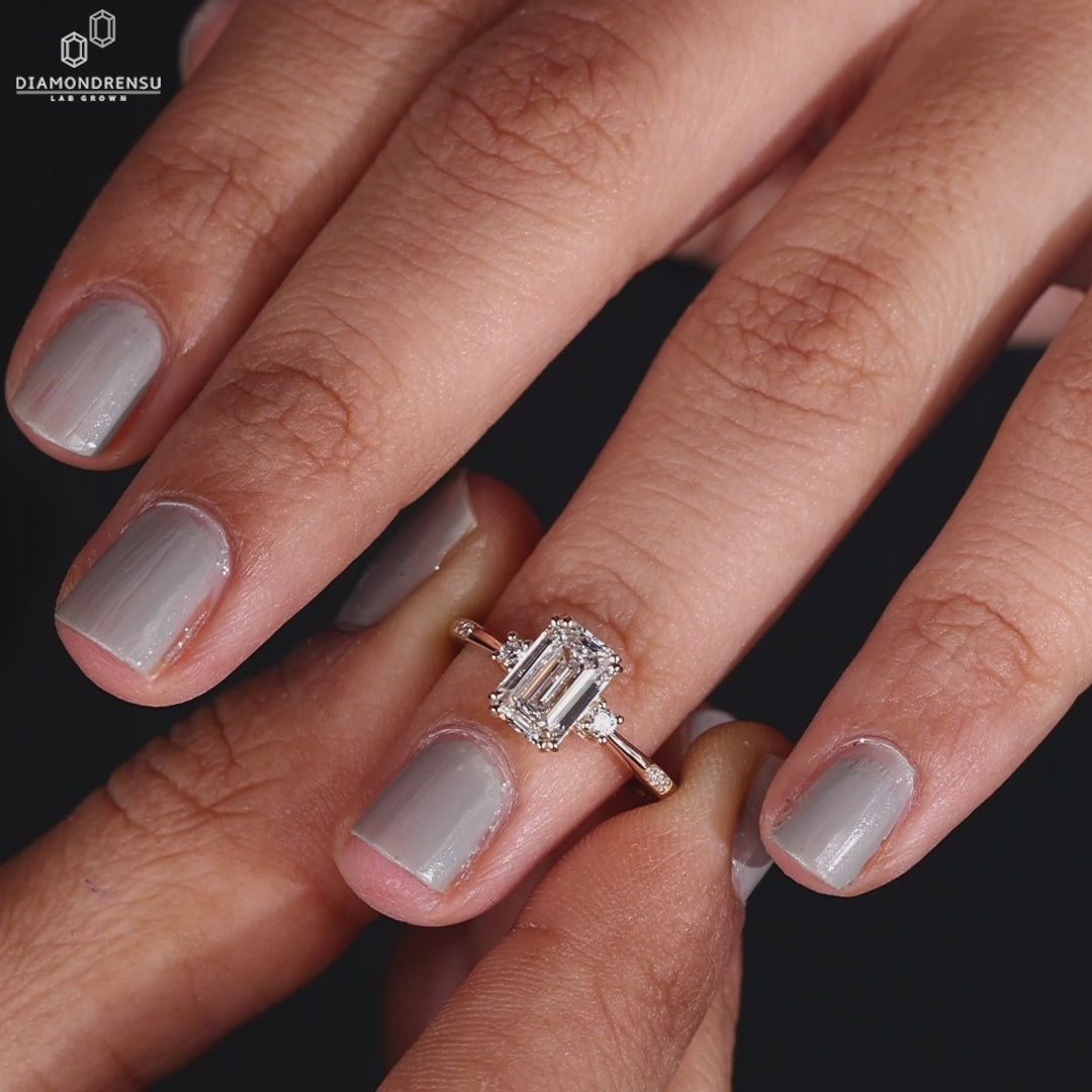 Woman's hand displaying a three stone ring with emerald cut diamonds