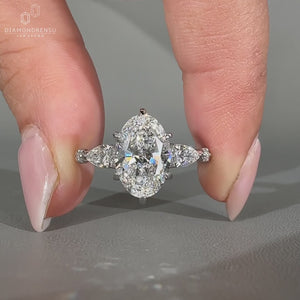 Five stone ring featuring oval cut diamond and pear side diamonds.
