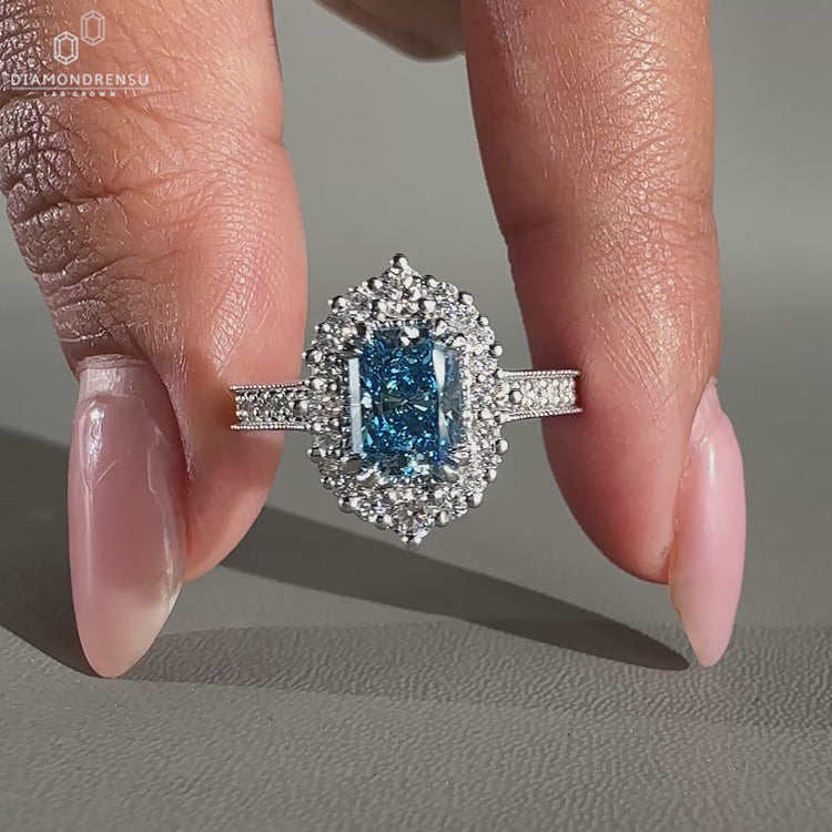 Blue diamond ring featuring round cut diamond in halo design
