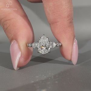 Side stone engagement ring with pear center diamond.

