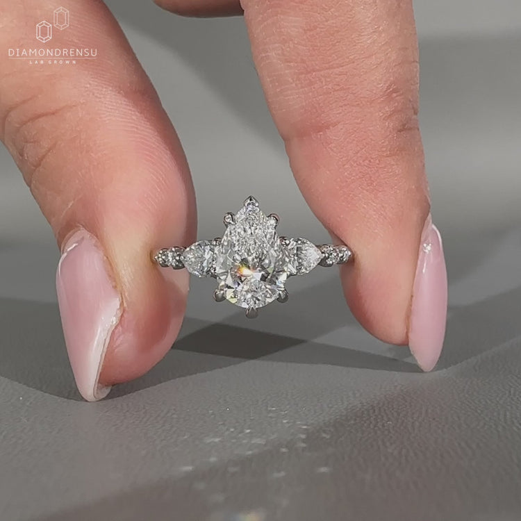 Side stone engagement ring with pear center diamond.
