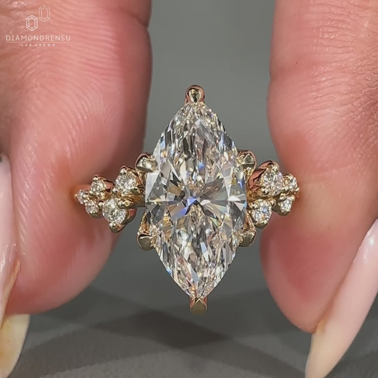 Round cut side stones set in a marquise cut engagement ring with 6 claw prong setting and yellow gold engagement ring.
