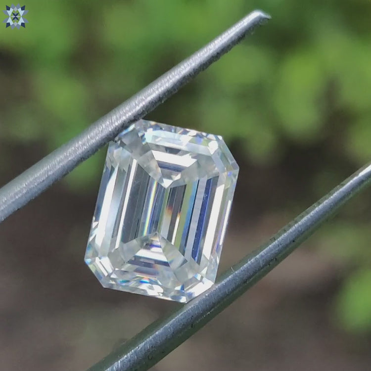 Moissanite emerald cut loose stone beside emerald cut loose moissanite.
