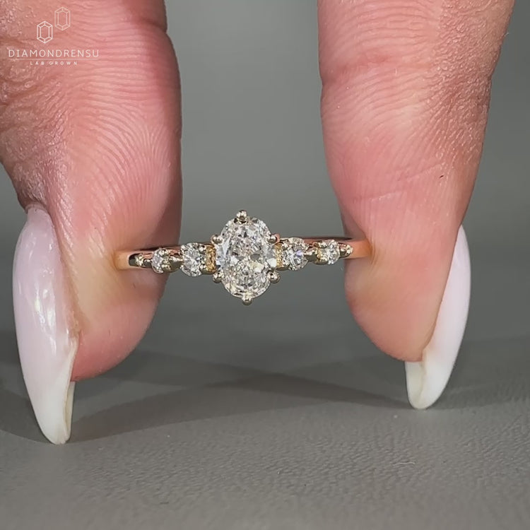 Oval cut diamond ring with round cut side stones in yellow gold.
