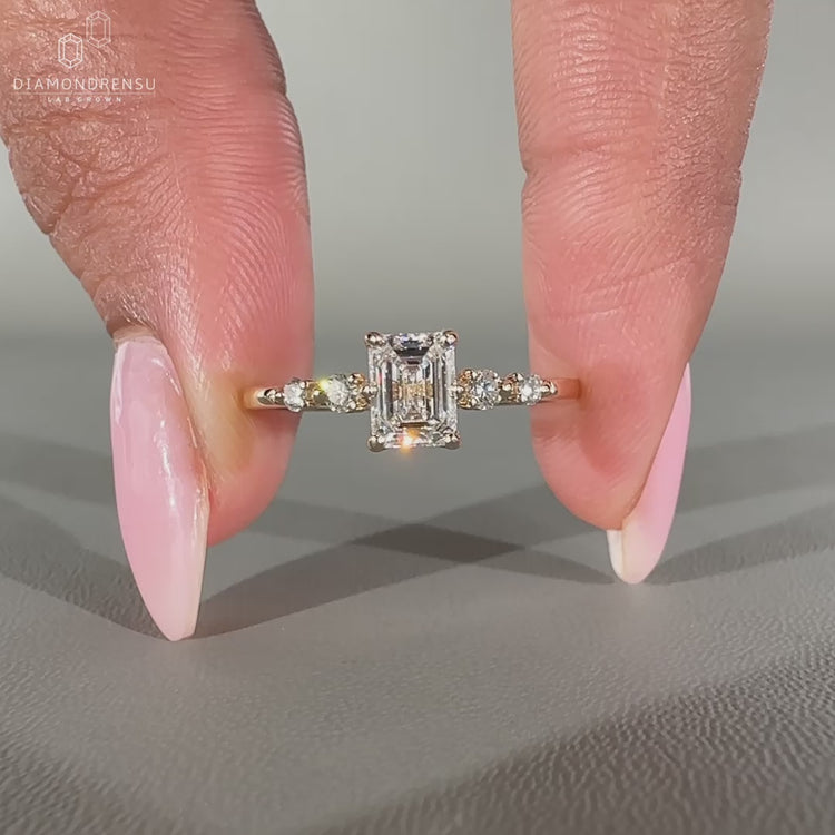 Emerald cut diamond ring with round side stones.
