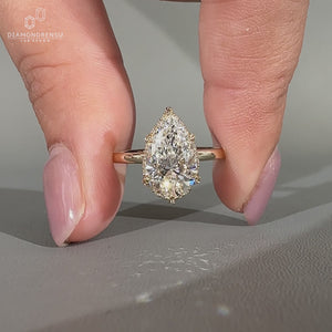 Hidden halo ring with solitaire pear cut diamond in yellow gold.
