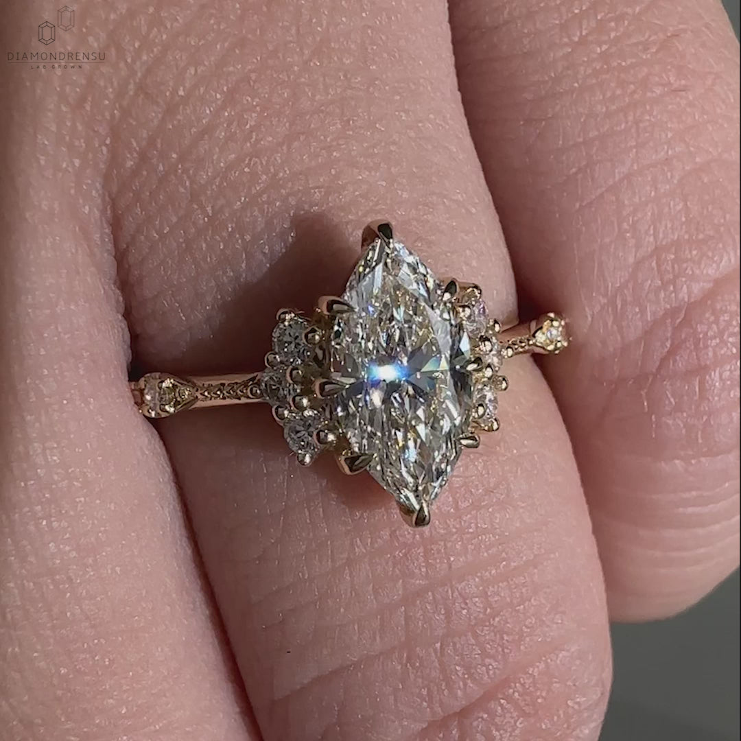 Close-up of a woman wearing a vintage engagement ring with a marquise cut diamond and round sidestones, showcasing claw prongs and miligrain detailing.