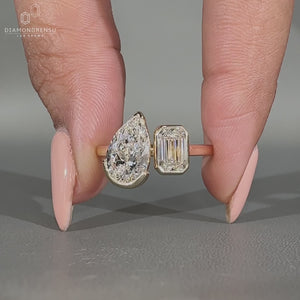 Pear and emerald toi et moi engagement ring bezel set.