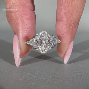 White gold engagement ring with marquise and round side stones in prong setting.