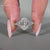 White gold engagement ring with marquise and round side stones in prong setting.