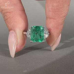Green emerald cut diamond ring with half moon side stones.
