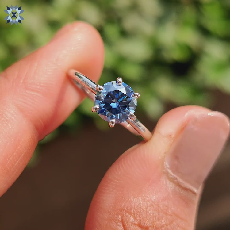 Round cut moissanite ring with a royal dark blue center stone.
