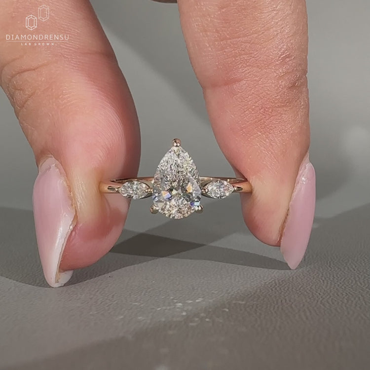 Pear center diamond ring with marquise side diamonds and tapered shank.
