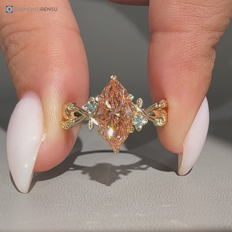Marquise diamond ring with pink center stone and round sides.