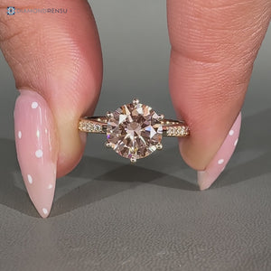 Pink center stone complements this round diamond ring.