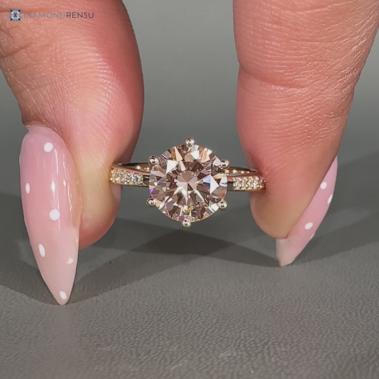 Pink center stone complements this round diamond ring.