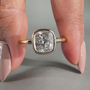 Cushion diamond ring set in a bezel engagement ring for a sleek design.
