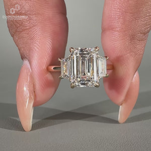 Three stone anniversary ring featuring a beautiful emerald cut diamond center.
