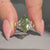 Green marquise center stone in a tulip setting.