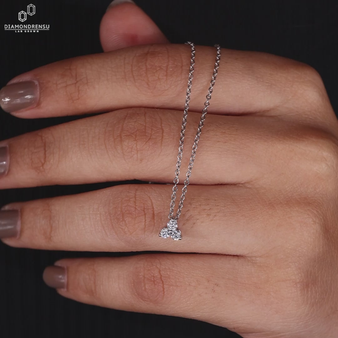 Hand displaying a round diamond pendant, highlighting its sparkling facets and delicate chain.