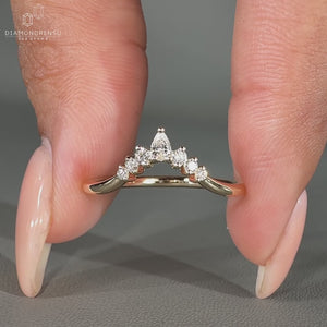 Elegant pear and round diamond band resting in a velvet ring box.
