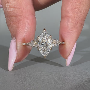 Muse setting ring featuring marquise diamond and round side stones.
