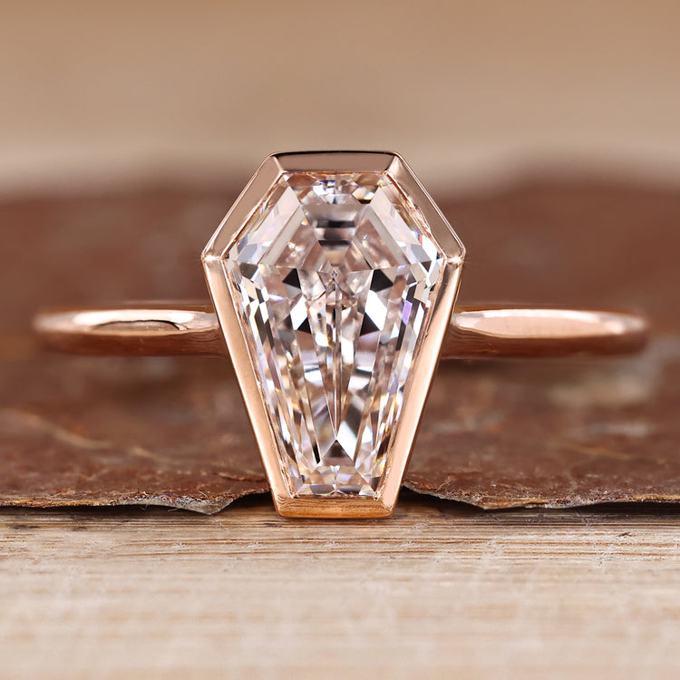 Solitaire diamond ring with coffin cut diamond and bezel setting.