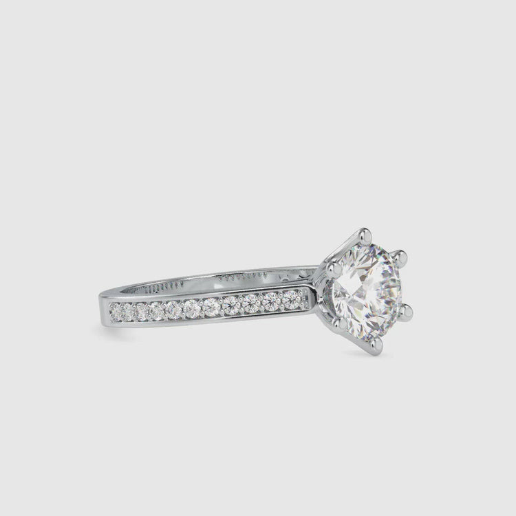 Six prong diamond engagement ring with a pave setting and round brilliant cut diamond.