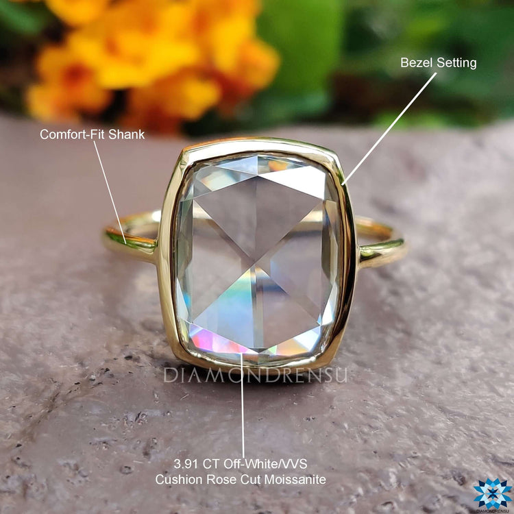 A bezel set engagement ring featuring a solitaire moissanite stone in a classic yellow gold band.