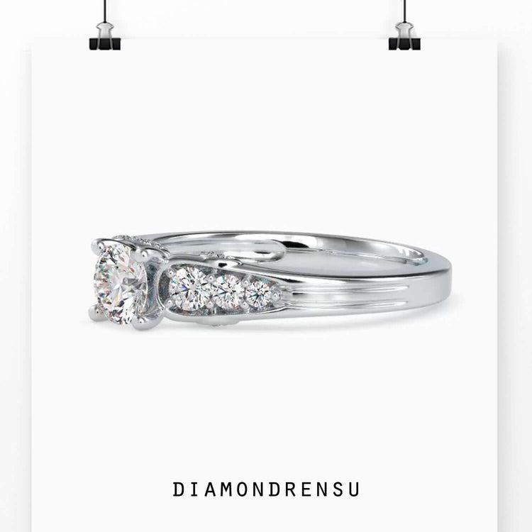 Tapered diamond engagement ring with brilliant cut center and side stones.
