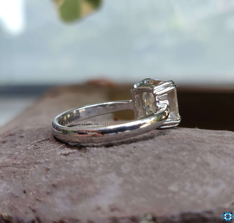 Moissanite Asscher cut engagement ring shimmering in natural light.
