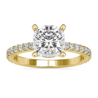Cushion cut diamond ring with a pave diamond band and basket setting.
