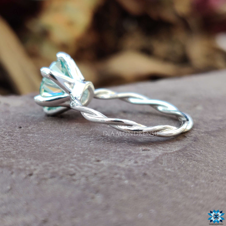 Round solitaire engagement ring with delicate twist details.
