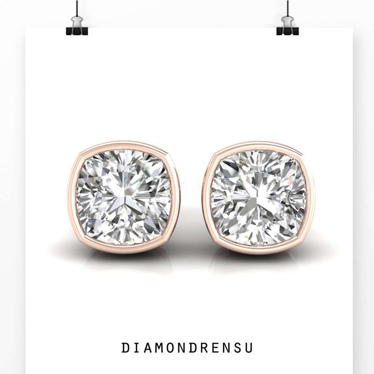 Handmade bezel set stud earrings with cushion cut diamonds for a refined finish.

