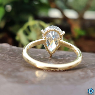 An elegant pear shape engagement ring set with a hidden halo and claw prong setting in yellow gold.
