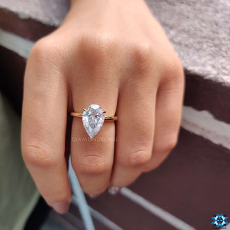 A claw prong engagement ring showcasing a pear-shaped centre stone, complete with a hidden halo.